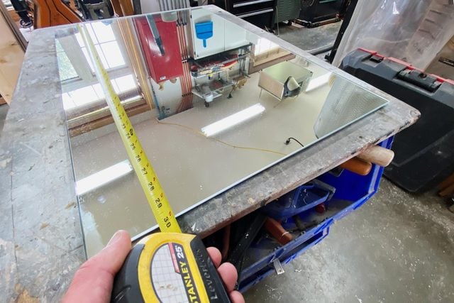 measuring the mirror with a tape measure