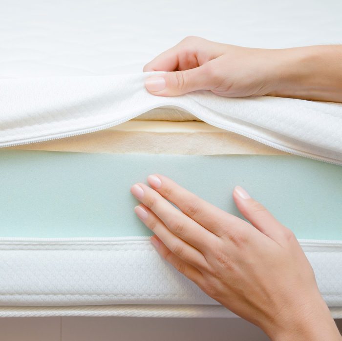 Woman's hands touching different layers of new mattress. Checking hardness and softness. Choice of the best type and quality. Front view. Close up.
