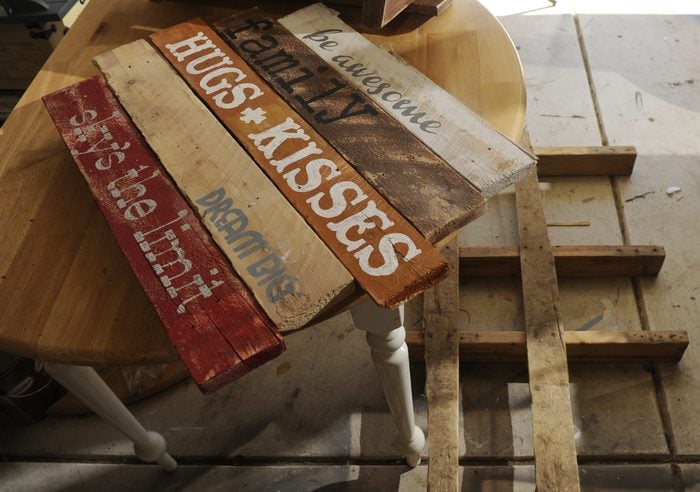 Kim Hanou creates her recycled art for home goods out of wooden pallets at her garage at her Arvada home on Monday, July 23, 2012. On the table is a sign she has created and on the ground is a pallet as it is getting pulled apart. Hanou sells them through