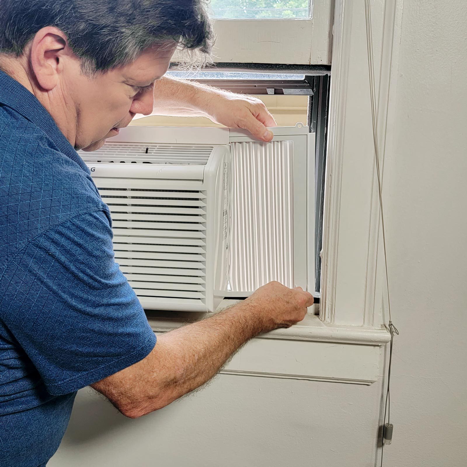 man Expanding the wings on the air conditioner to close the gap on each side