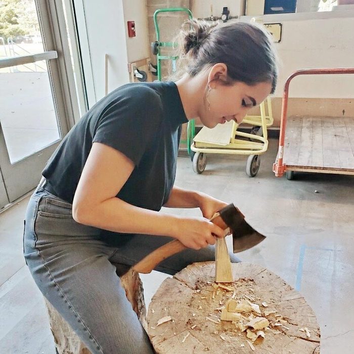 Melinde madsen using an ax to shape some wood