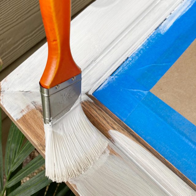putting primer on a wooden frame with a paint brush