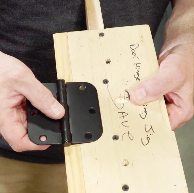 hands holding a hinge on a piece of wood making a door hinge template