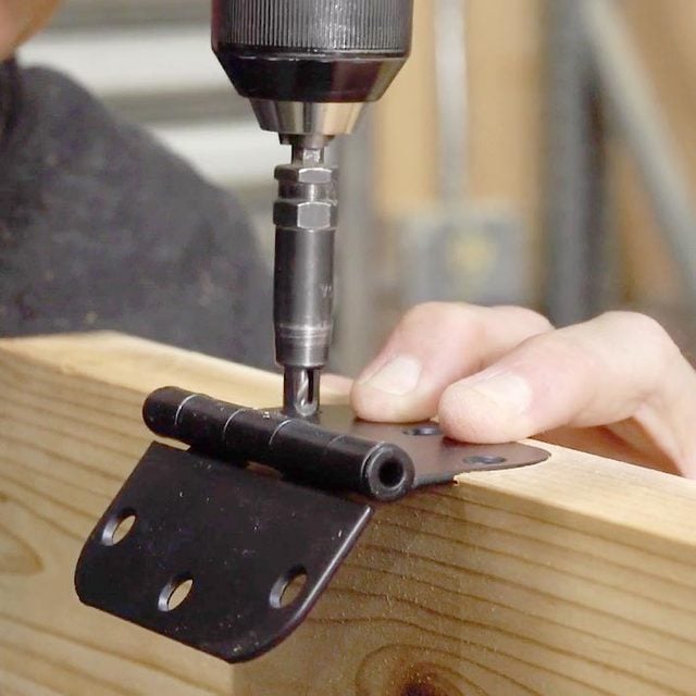 using a drill to attach the hinge