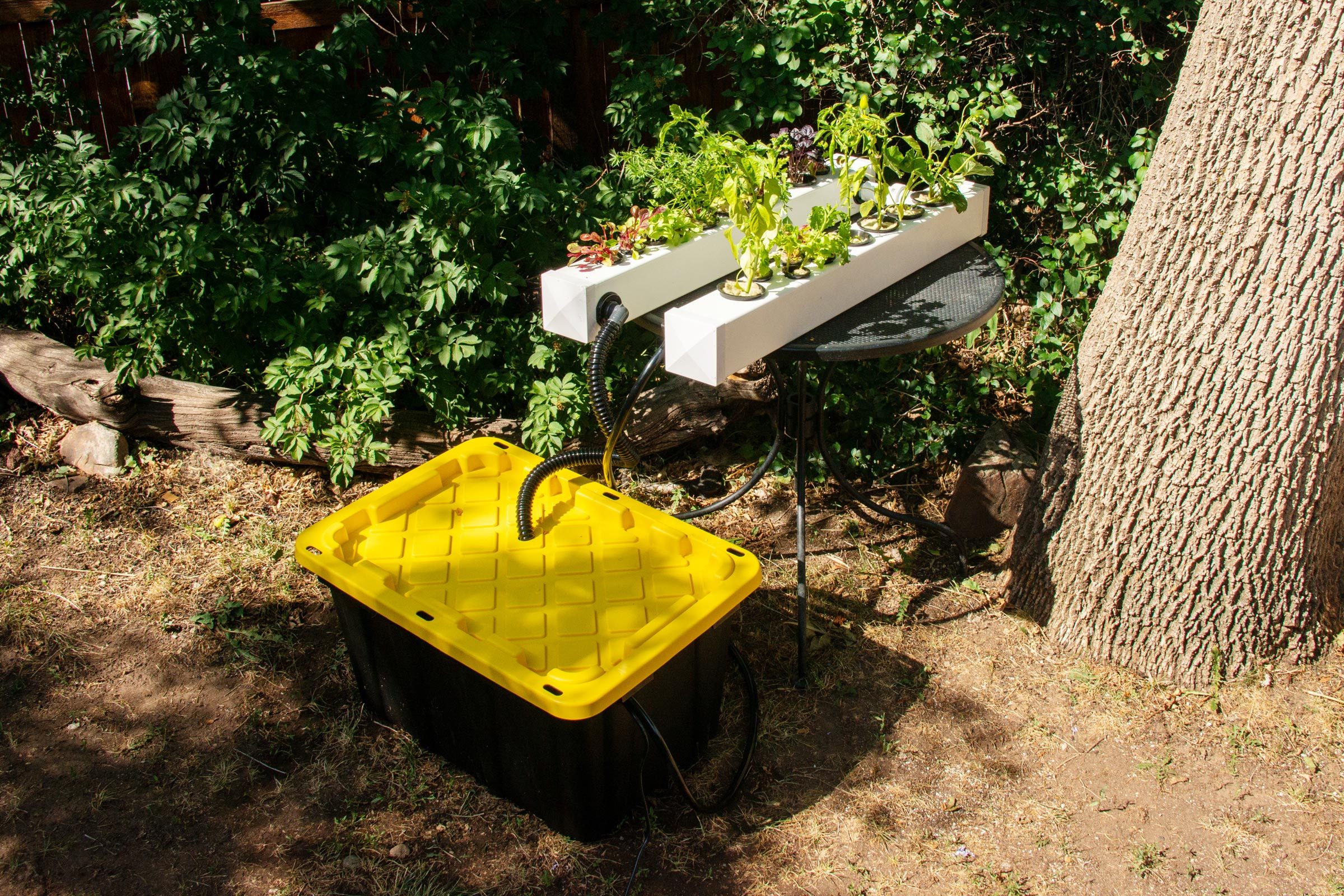 a finished DIY hydroponic garden sitting on an outdoor table next to a tree