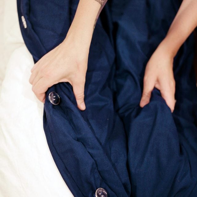 close up of hands stuffing a duvet into the blue duvet cover
