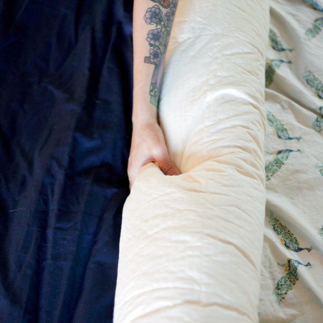 close up of hands rolling a duvet insert into a burrito shape