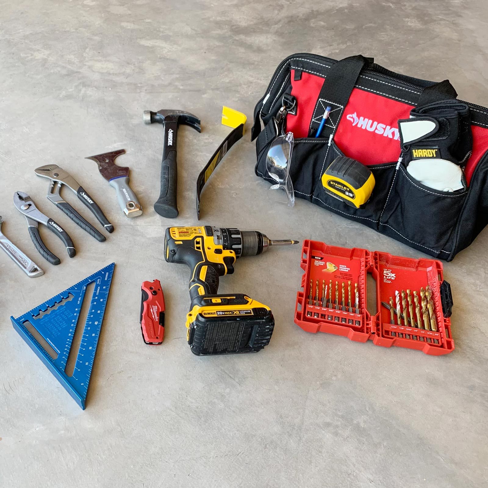 tool bag and tools spread out on a concrete floor
