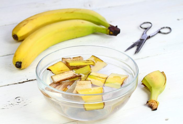 banana peels in a bowl of water with a bunch of bananas in the background