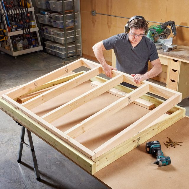 man building sauna walls in a workshop
