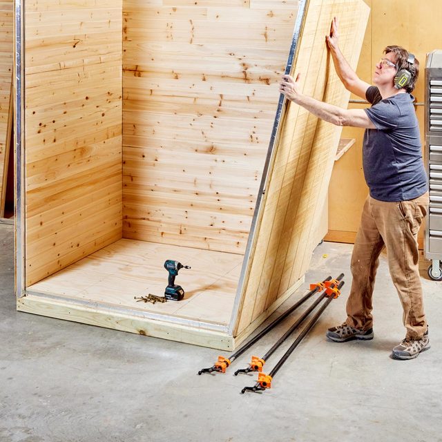 man in a workshop assembling three sauna walls together
