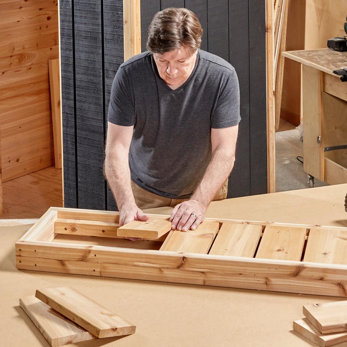 man in a workshop building a bench for the sauna with cedar wood planks