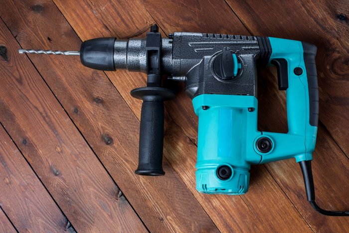 Industrial hammer drill. Perforator with a drill on a wooden background.