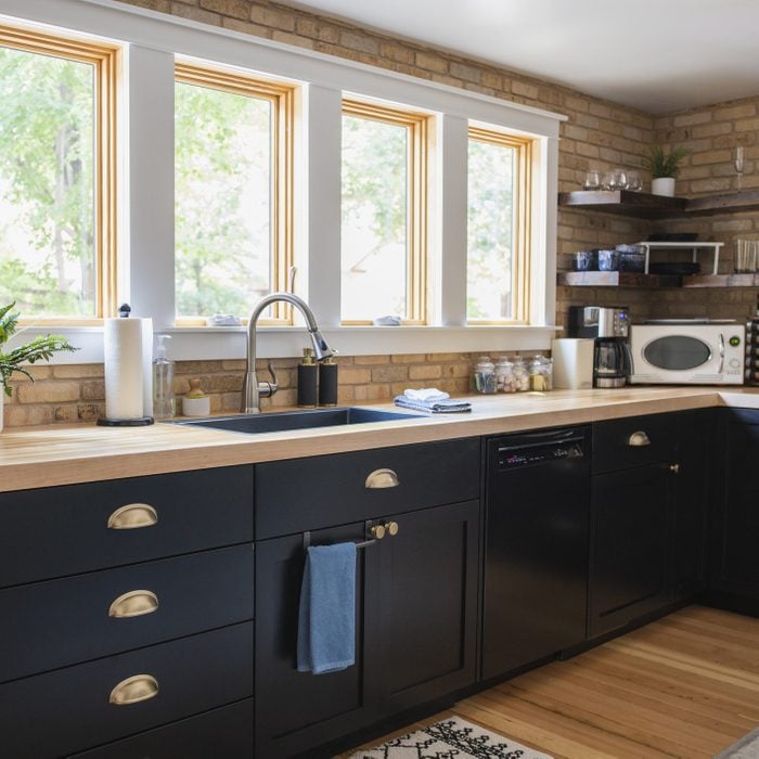 Home kitchen interior with black cabinets and a light brick backsplash