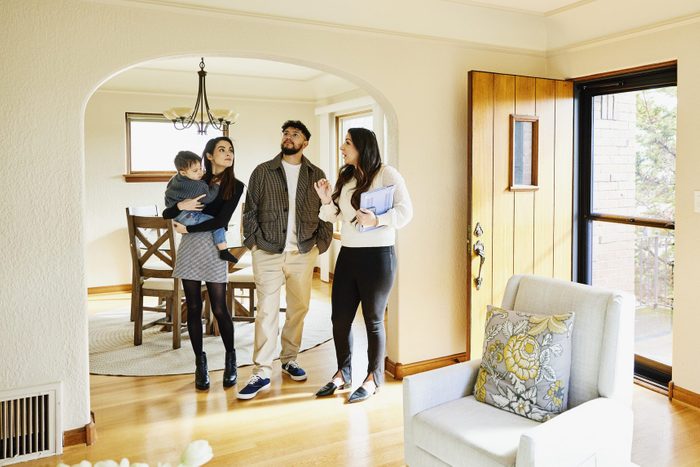 Wide shot of family looking at home for sale with real estate agent