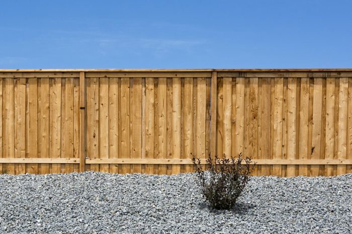 board on board wooden Fence with a gravel garden in front and blue sky
