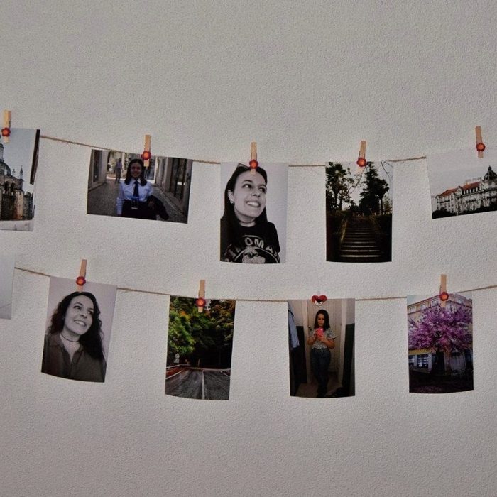 Photographs Hanging On Strings Against White Wall