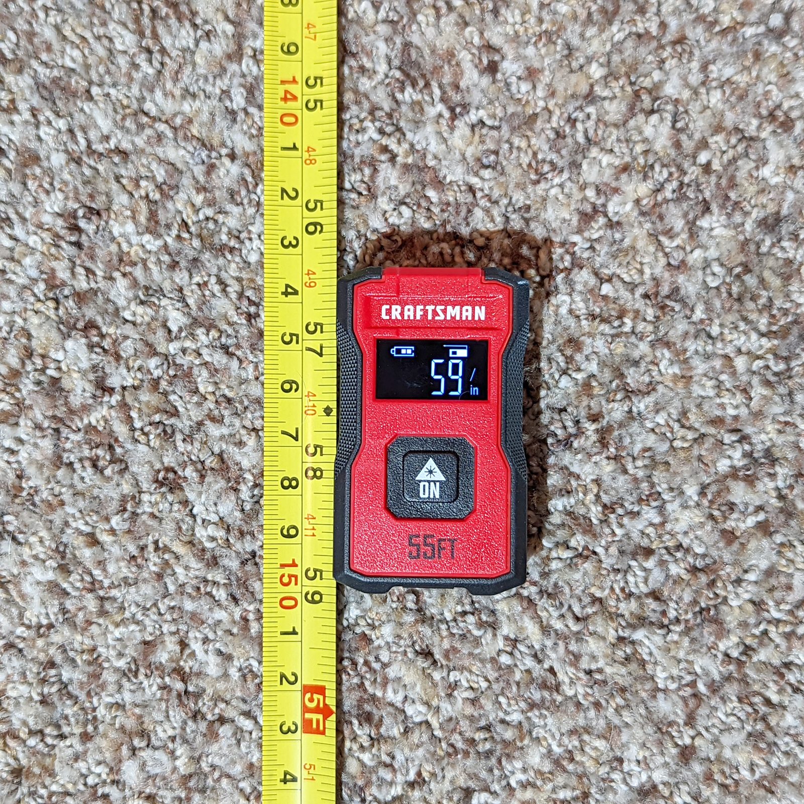 Craftsman Ldm next to a yellow tape measure showing it is 2.5 inches long
