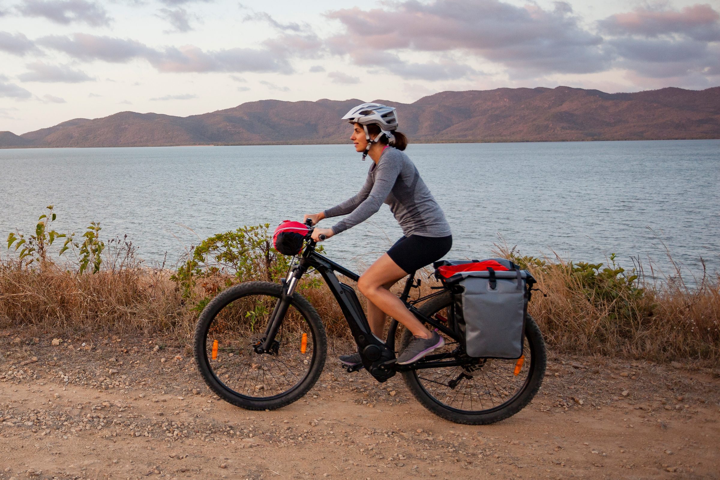 woman riding an e bike next to a lake and mountains