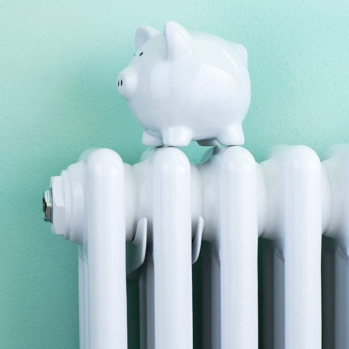 a piggy bank sitting on a radiator in a house with a teal colored wall