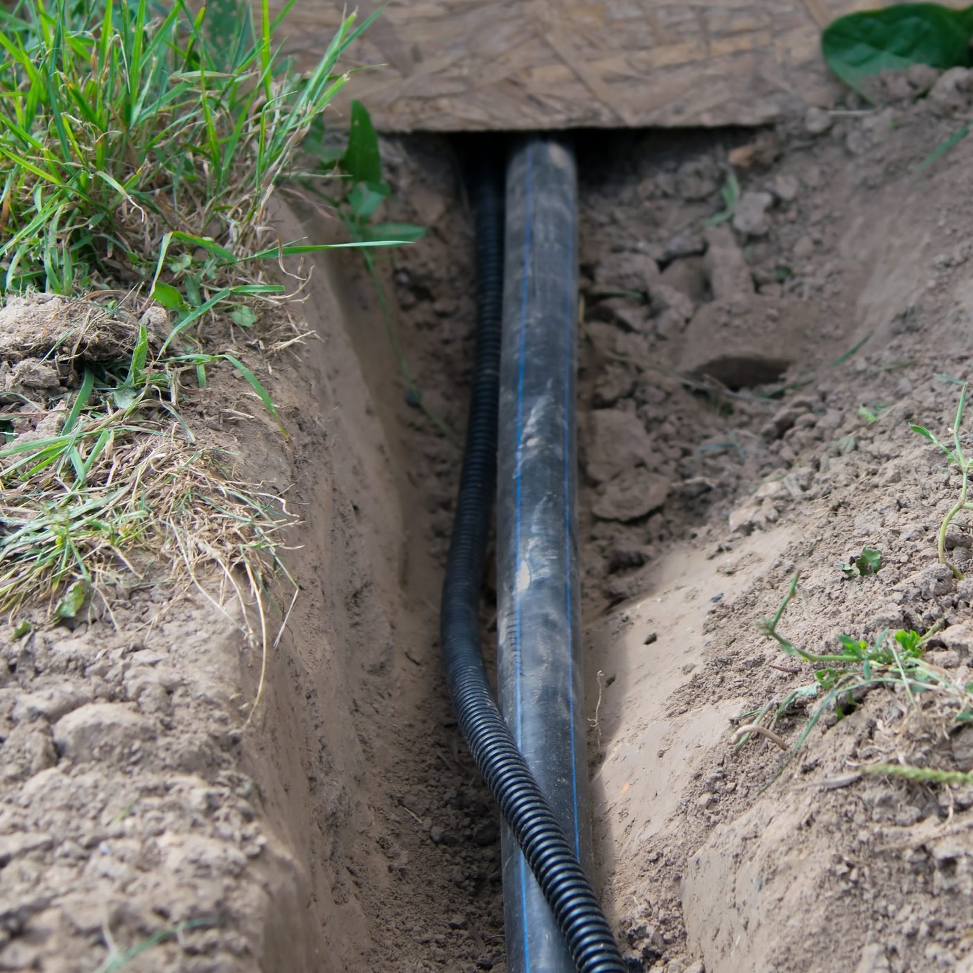 close up of two wires being run underground from under a deck