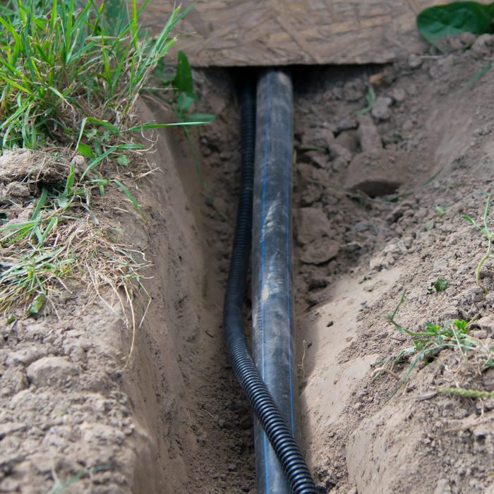 close up of two wires being run underground from under a deck