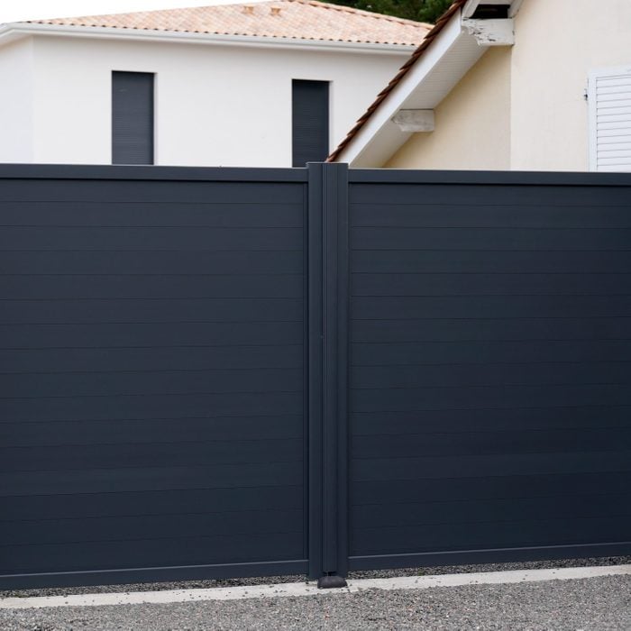 black vinyl fence gate in front of a white modern house