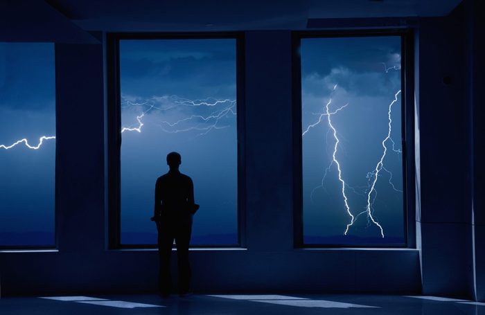 Man Standing In Window During Storm