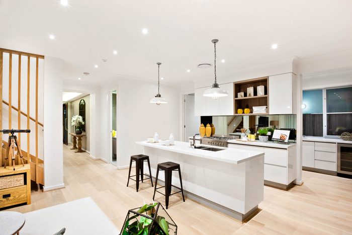 Modern kitchen with white walls illuminated by hanging lamps