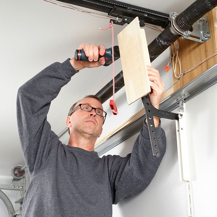 man covering his garage door hook with plywood