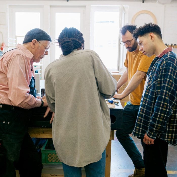A group of students learning about different aspects of wood working and the relevant from a mature technician in his studio