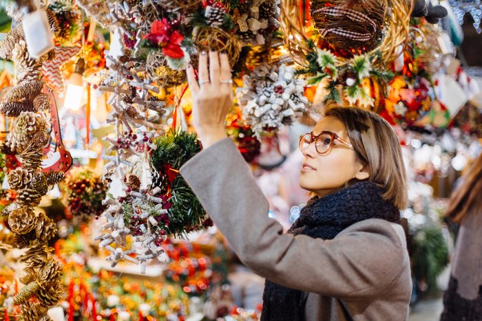 Young Woman Choosing Christmas Decoration On A Christmas Market In Barcelona, Spain