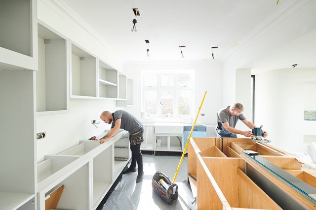 two men working on installing a kitchen