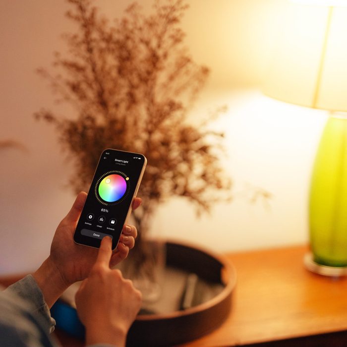 anonymous hands using smartphone to adjust the lighting equipment of a modern smart home