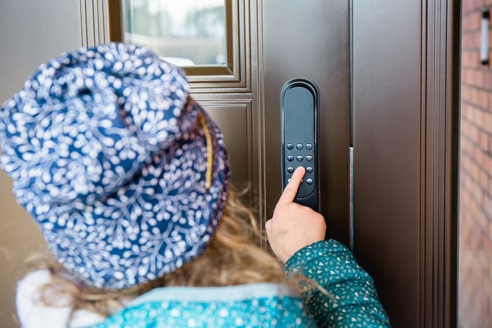 Girl child opening home smart door lock, unlocking the code. Close up view of girl touching pointing the number pad.