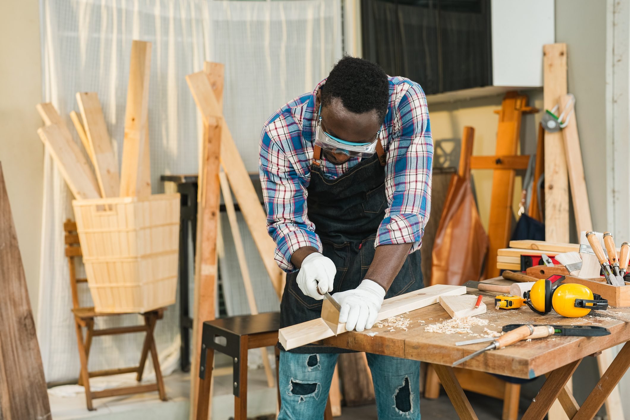 Man cutting through block of wood using saw, close-up of hands