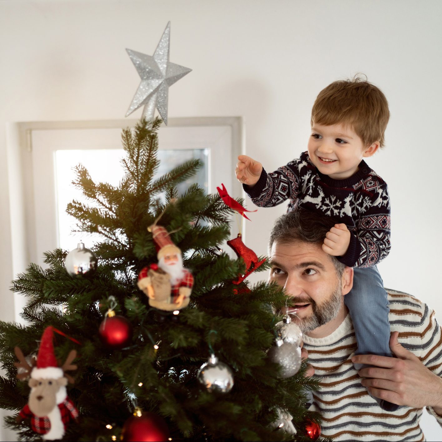 Father and his toddler son decorating a Christmas tree together