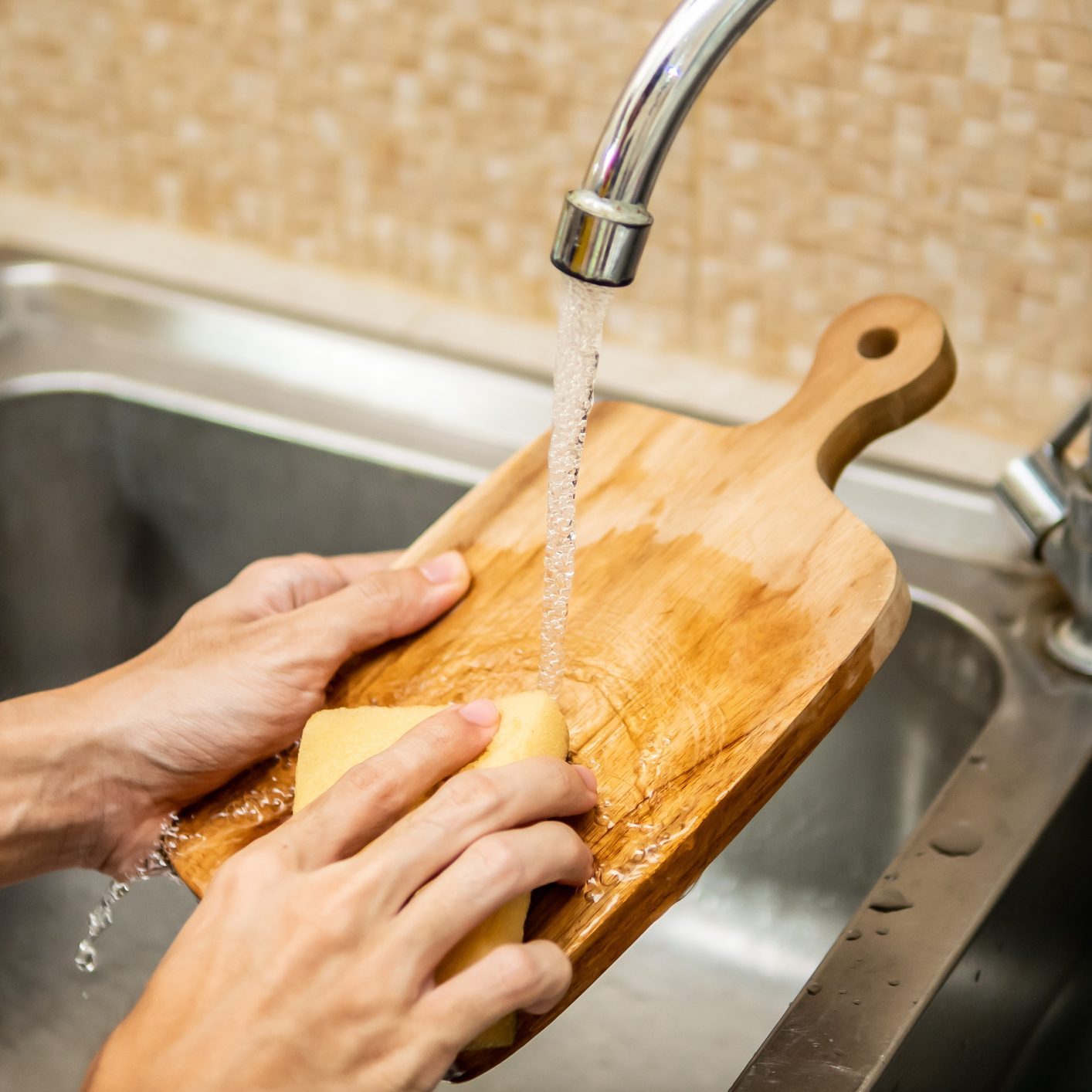 Чистка деревянной разделочной доски в кухонной раковине