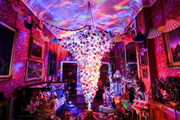 room filled with gifts with an upside down christmas tree aglow in the center, hanging from the ceiling