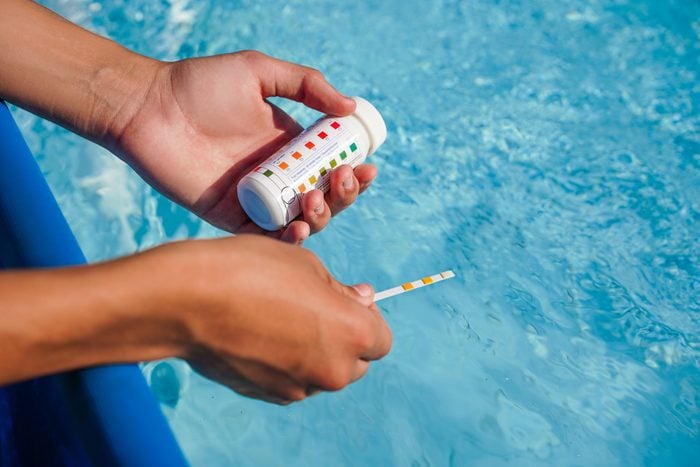 hands checking the PH balance in a swimming pool with a test strip