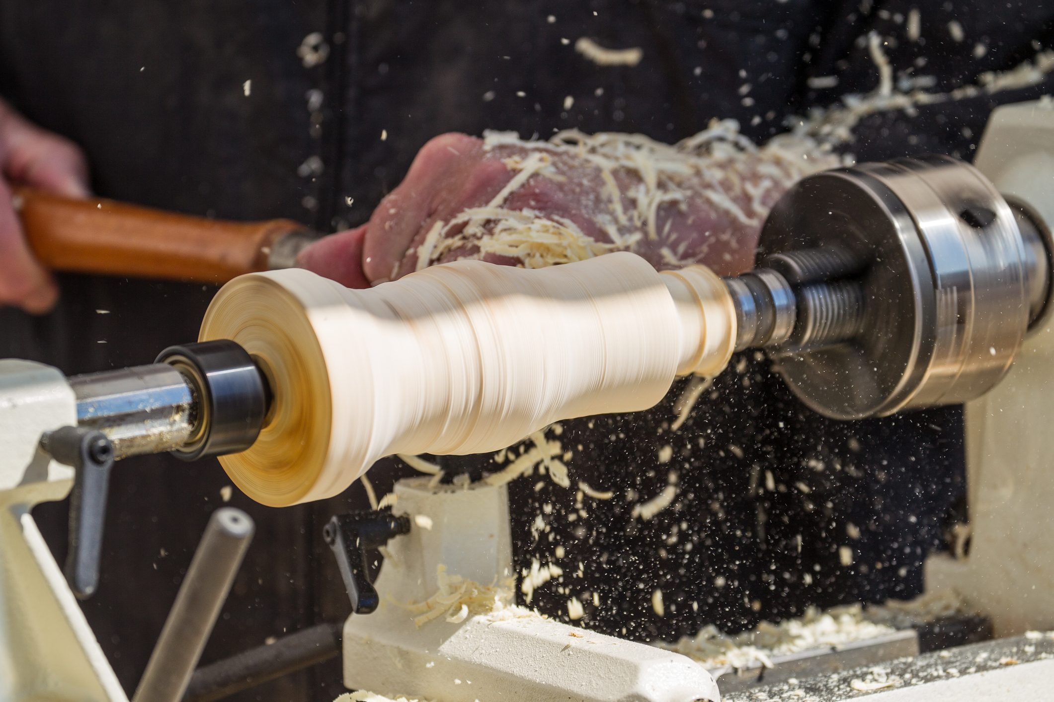 A man shapes a spindle on a lathe.
