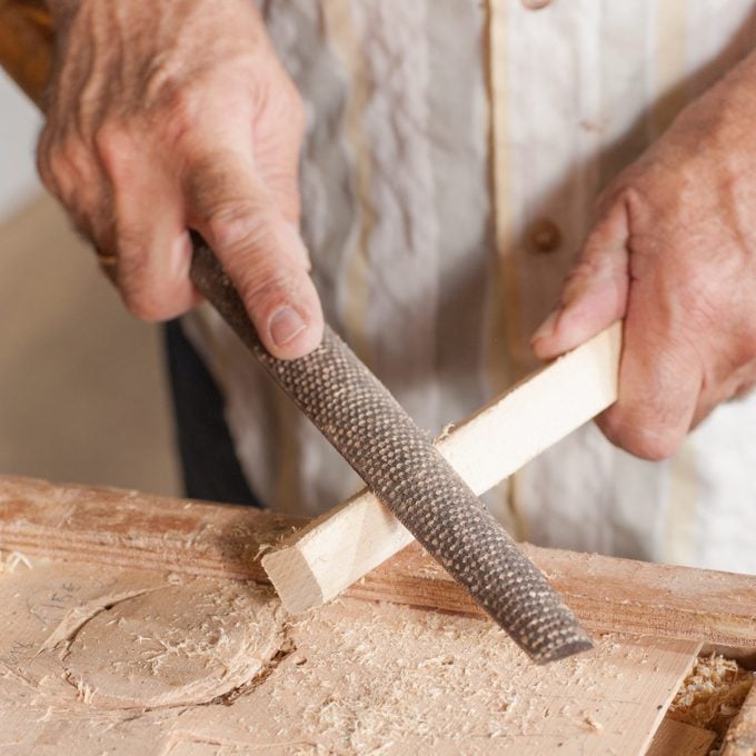 Carpenter working with a traditional rasp tool