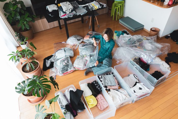 Woman organizes clothes in living room of her home