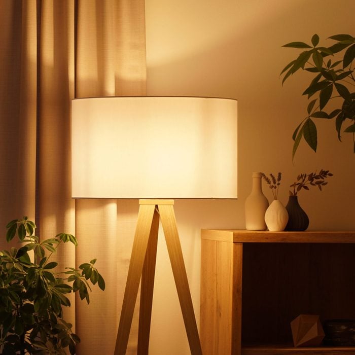 View of tripod lamp in a cozy living room spending warm light