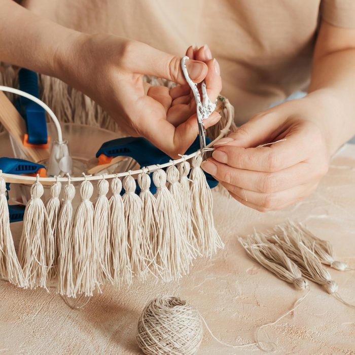 woman makes a lamp shade with handmade tassels.