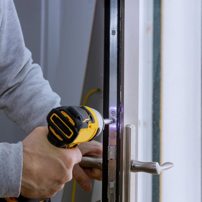 Man installing new door lock on exterior door