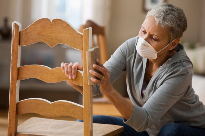 Mixed race woman refinishing chair inside home