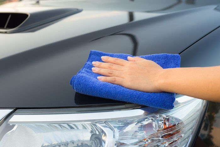 Girl's hand wiping on surface of car with a microfiber towel