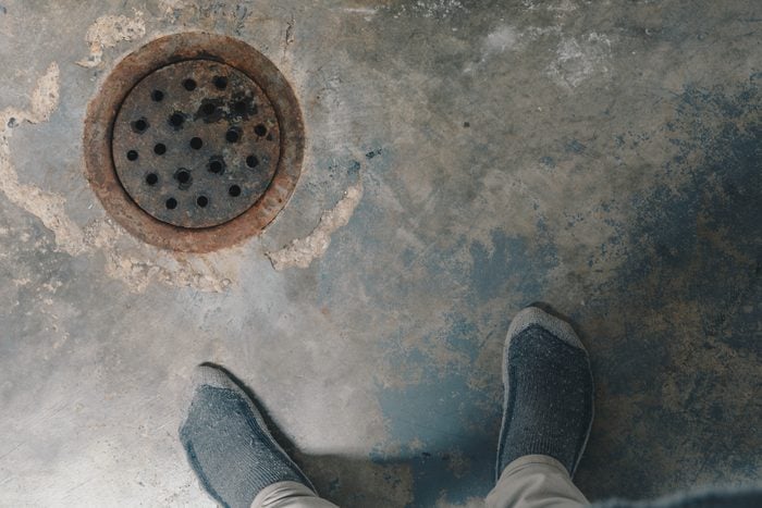 Low Section Of Man Standing By Sewer In Basement