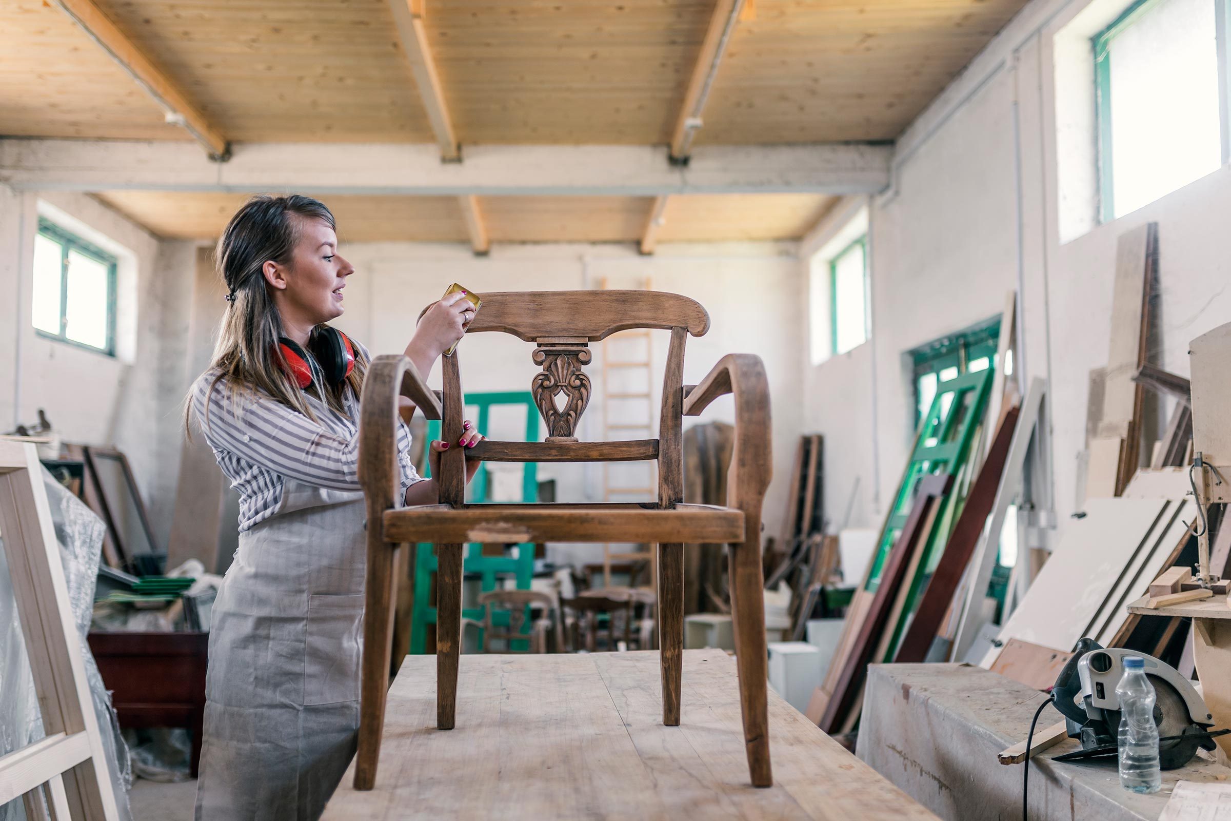 Female Master Carpenter renovates old wooden armchair